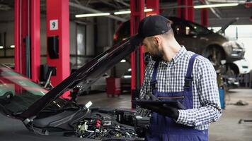 Man at the workshop in uniform using tablet for his job for fixing broken car video