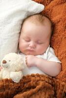 un recién nacido bebé duerme en un cama. un osito de peluche oso mentiras cercano. madre y niño. foto