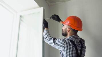 A repairman in uniform and helmet fixing pvc windows in new apartment video