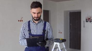 Young foreman builder, engineer or inspector checking and inspecting with clipboard at construction site building interior before complete new project. Contractor and engineering concept video