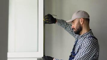 Worker installs and adjusts a new plastic window in house. Repairman regulates Installation and adjustment video
