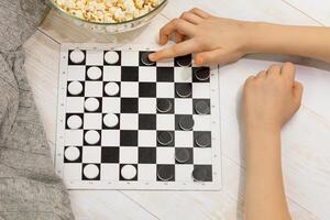 A chess board with checkers and a child's hand making a move photo