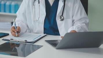 Doctor and nurse examining patient's medical records and medical team working on the background video