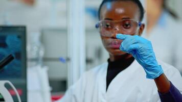 Black technician doing experiment in modern equipped lab looking at result. African scientist working with various bacteria tissue and blood samples, concept of pharmaceutical research for antibiotics video