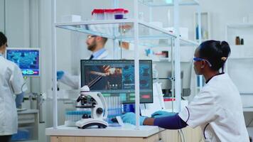Black scientist making research for new vaccine in modern equipped lab. Multiethnic team examining virus evolution using high tech for scientific research of treatment development against covid19. video
