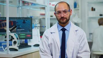 Tired doctor looking exhausted at camera in modern equipped lab. Multiethnic team examining virus evolution using high tech and chemistry tools for scientific research, vaccine development. video