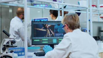 Medical research scientist typing codes on pc in biological applied science modern equipped laboratory. Lab engineers in white coats conducting experiment for vaccine development against covid19 virus video