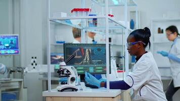 African laboratory scientist working in modern equipped lab with test tubes. Multiethnic team examining virus evolution using high tech for scientific research of treatment development against covid19 video
