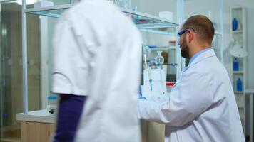 Biologist doctor checking DNA samples in modern equipped laboratory. Multiethnic team examining vaccine evolution in medical lab using high tech and chemistry tools for scientific research. video