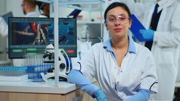 Portrait of scientist smiling at camera sitting in modern equipped laboratory. Multiethnic team examining virus evolution using high tech and chemistry tools for scientific research, vaccine development. video