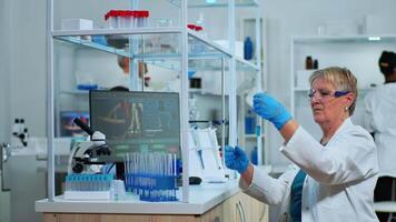 Microchemist doing research checking liquid in test tube typing results on pc in modern equipped lab. Multiethnic team examining virus evolution using high tech for vaccine development against covid19 video