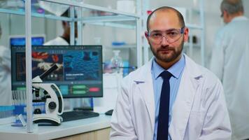 Portrait of exhausted chemist looking at camera in modern equipped lab. Multiethnic team examining virus evolution using high tech and chemistry tools for scientific research, vaccine development. video