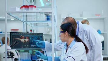 Research scientists working on pc with medical equipment analyzing blood and genetic material samples with special program in modern equipped laboratory. Multiethnic team examining virus evolution video