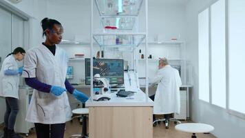 Medical multiethnic stuff testing covid19 vaccine in modern equipped laboratory. Diverse group of scientists analysing virus evolution using high tech and chemistry tools for researching treatment video