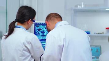 Team of scientists discussing about virus development in front of pc in modern equipped laboratory. Multiethnic stuff analysing vaccine evolution using high tech for researching treatment video