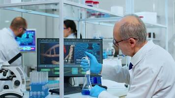 Chemist putting liquid in test tube with micropipette in modern equipped laboratory. Multiethnic team examining vaccine evolution using high tech and chemistry tools for virus development research video