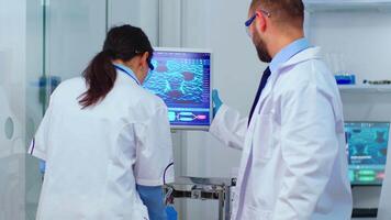 Scientist team arguing in front of computer looking at virus development in modern equipped laboratory. Multiethnic stuff analysing vaccine evolution using high tech for researching treatment. video