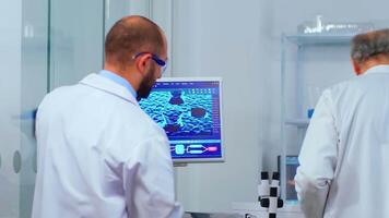 Team of scientists worried about virus evolution discussing in modern equipped laboratory. Multiethnic stuff examining vaccine development using high tech researching treatment against covid19 virus video
