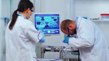 Team of experienced biologists working on microscopes in modern equipped laboratory. Scientists stuff examining vaccine evolution using high tech researching diagnosis against covid19 virus video