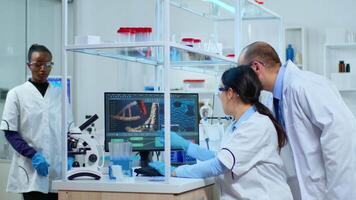 equipe do microbiologia cientistas discutindo sobre vírus desenvolvimento dentro moderno equipado laboratório usando computador analisando teste sangue amostras e desenvolve vacina, drogas e antibióticos contra COVID-19. video
