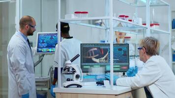 Multiethnic team working to develop a new vaccine in modern equipped laboratory. Diverse group of biochemistry scientists examining virus evolution using high tech for researching treatment video