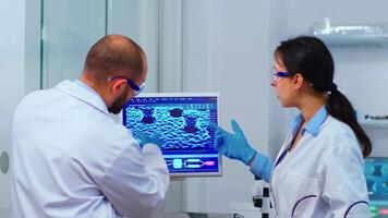 Scientists coworkers working in chemical modern equipped laboratory. Multiethnic stuff examining vaccine evolution using high tech and technology researching treatment against covid19 virus video