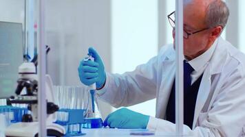 Laboratory senior man scientist working with test tubes and a pipette in equipped laboratory. Scientist analysing various bacteria, tissue and blood samples, pharmaceutical research for antibiotics video