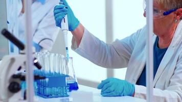 Scientist in modern equipped medical laboratory examinining drug discovery with micropipette. Multiethnic stuff examining vaccine evolution using high tech and technology researching treatment video