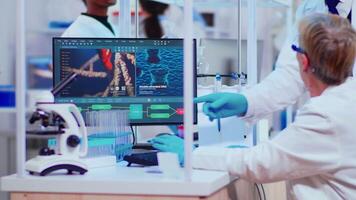 Senior woaman biochemist checking manifestations of virus working in modern equipped laboratory. Team of doctors examining vaccine evolution using high tech researching diagnosis against covid19 video
