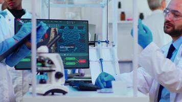 Team of multiethnic positive scientists working in chemistry modern equipped laboratory. Group of doctors examining vaccine evolution using high tech researching diagnosis against covid19 virus video
