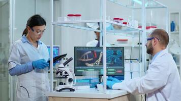 Scientist nurse taking notes on tablet in modern equipped laboratory. Multiethnic team examining vaccine evolution using high tech for research in treatment development against covid19 virus video