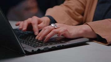 Close-up of businesswoman hands sitting at desk table in business company office typing financial strategy on laptop computer late at night. Tired executive manger programming marketing meeting video