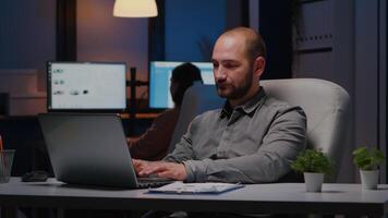 retrato do homem de negocios trabalhando em computador portátil computador planejamento financeiro estratégia atrasado às noite dentro o negócio companhia escritório. viciado em trabalho Gerente sorridente para dentro Câmera enquanto sentado em chiar video