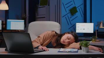 Businesswoman sleeping on desk while working at accounting statistics in business company office late at night. Overworked, stressed exhausted employee at workplace napping on overtime video