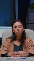Pov of tired entrepreneur woman sitting at desk table having business webinar discussing financial strategy during videocall teleconference meeting. Businesswoman working overtime in company office video