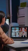 Overworked manager working in startup business office discussing with virtual teamwork on laptop during online teleconference meeting. Entrepreneur woman having marketing conference late at night video