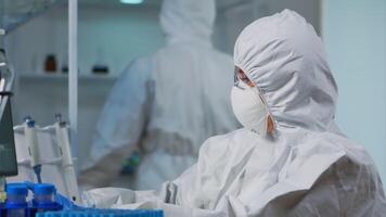 Close up of scientist in protection suit typing on pc working in medical laboratory, developing inovative drugs. Doctor using high tech, chemistry tools for scientific research, against new virus video