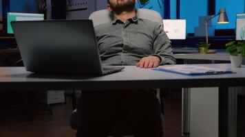 Workaholic businessman slepping on chair in business company office late at night after checking financial statistics on laptop computer. Exhausted manager working overworked at economic project video