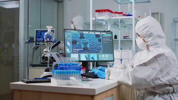 Medical research scientist in ppe suit typing codes on pc in biological applied science modern equipped laboratory. Lab engineers conducting experiment for vaccine development against covid19 virus video