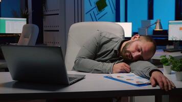 Exhausted overworked businessman sleeping on desk table in startup business office after planning management statistics late at night. Workaholic entrepreneur working at economic deadline project video