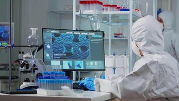 Chemist in ppe suit typing on computer checking virus development in modern equipped laboratory. Doctor working with various bacteria, tissue and blood samples, pharmaceutical research for antibiotics video