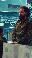Vertical Sergeant presenting his salute with respect for the colonel and high ranking military officers, saluting the captains while he works on intelligence in command center, pride and duty. Camera B. video