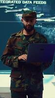 Vertical Special operations soldier allocating resources to different units based on mission needs, examines strategic data on a big screen in military control center. Marine corps troops. Camera B. video