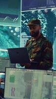 Vertical Army general managing air traffic control for military aircraft within the operational area, uses radar surveillance. Follows vessels on navy reconnaissance satellite system, big screen. Camera B. video