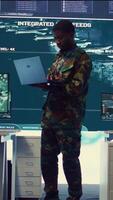 Vertical Military sergeant targeting enemy vessels on a gps satellite world map, operating from army power base monitoring room. Officer studies defense tactics on a tablet, command center. Camera B. video