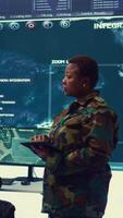 Vertical Woman high tech specialist studying satellite CCTV visualization on a big screen, preparing troops with insight for a new national safety mission. Female first lieutenant in command post. Camera B. video