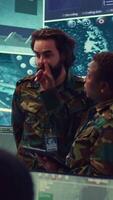 Vertical Diverse team of army officers reviewing important information from the enemy lines, ensuring advantage in a military command center. People using satellite surveillance in power base. Camera B. video