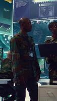 Vertical Army commanders overseeing field operations with real time data registered on surveillance CCTV systems. Military officials examining mission details, army defense program in power base. Camera B. video