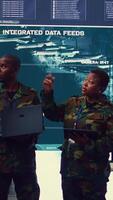 Vertical Sergeant major and female soldier checking real time field data in command post monitoring room, examining missions and operations. Team of troops interprets satellite imagery. Camera B. video