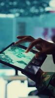 Vertical Army soldier reviews targets on a satellite world map to ensure global protection, works on tablet in military command center. Private examines battlefield data for intelligence. Close up. Camera B. video